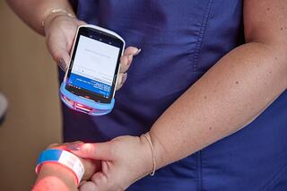 Worker scanning patient barcode with mobile computing solutions